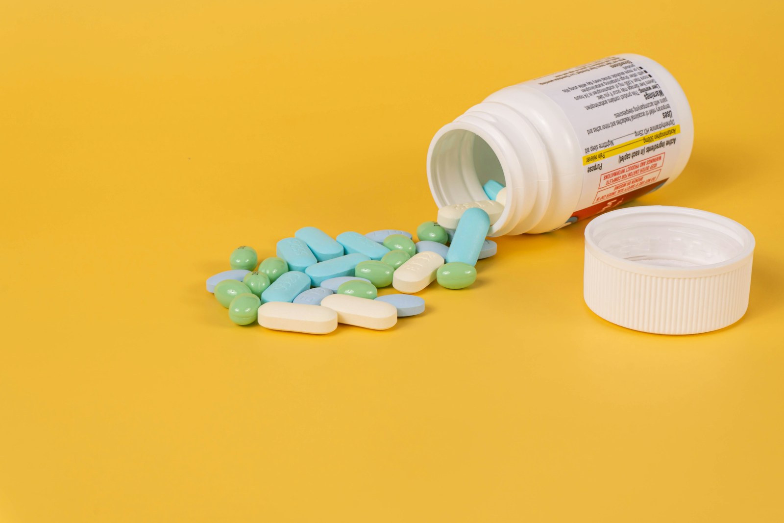 An open medication bottle with assorted tablets on a table.